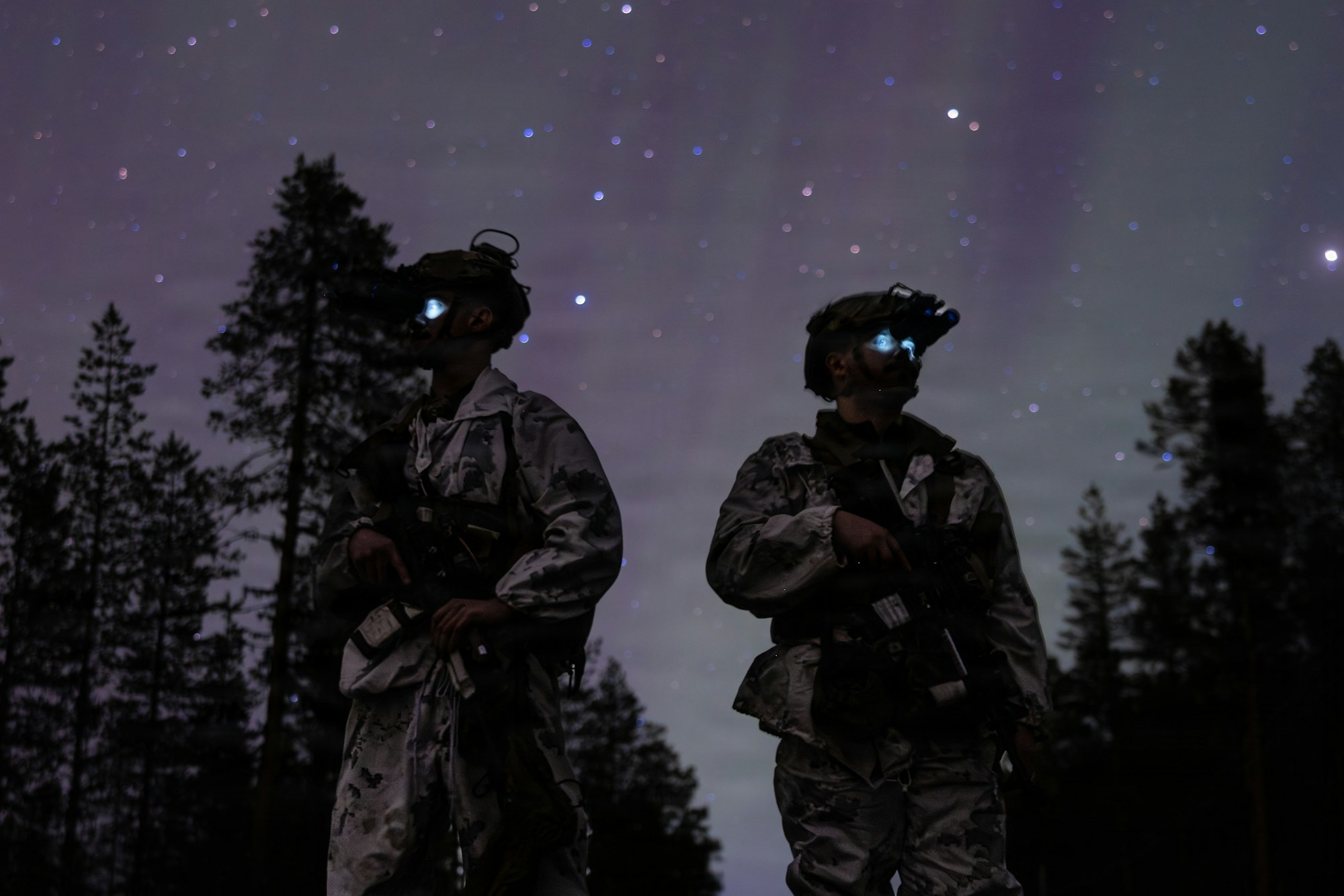 Two soldiers with night vision under a starry sky